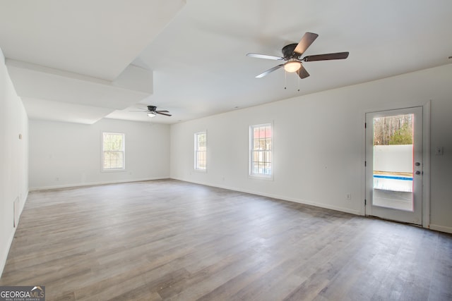 empty room featuring light wood finished floors, baseboards, and a ceiling fan