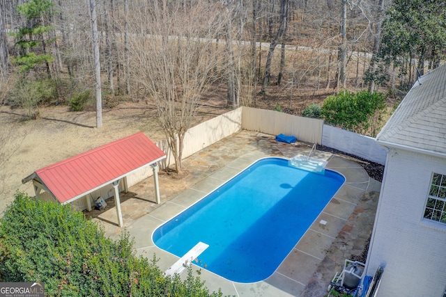 view of pool featuring a fenced in pool, a patio area, fence, and a diving board