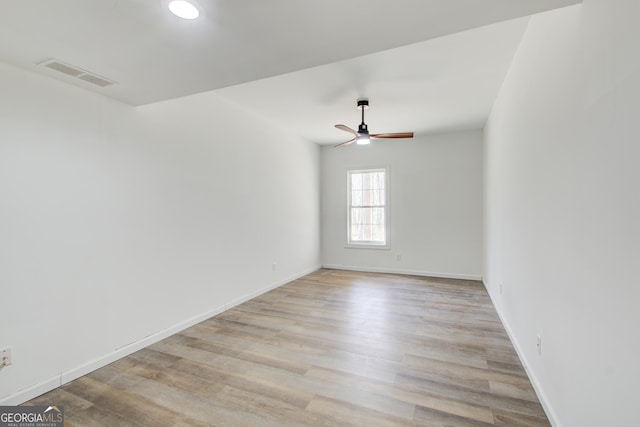 spare room with baseboards, light wood-style flooring, visible vents, and a ceiling fan