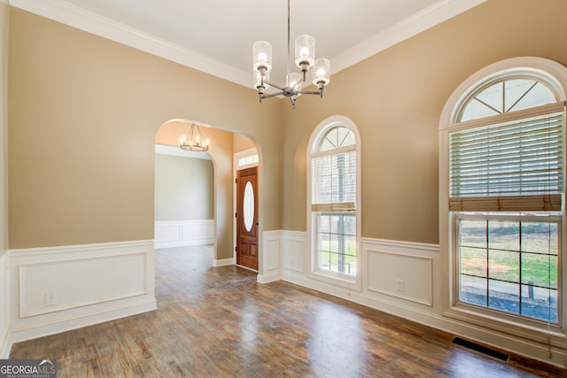 unfurnished dining area featuring a chandelier, visible vents, crown molding, and wood finished floors