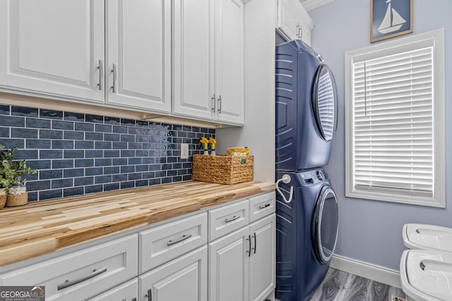 clothes washing area with cabinets, light hardwood / wood-style floors, and stacked washer and clothes dryer