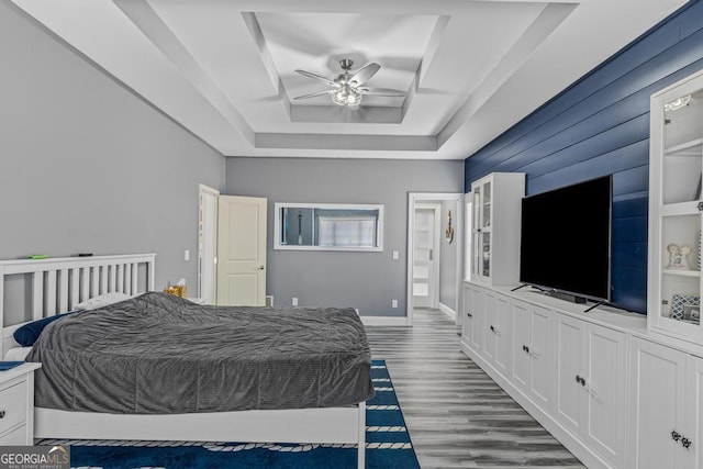 bedroom featuring ceiling fan, a tray ceiling, and dark hardwood / wood-style floors