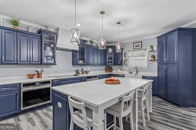 kitchen with blue cabinetry, pendant lighting, stainless steel oven, and a breakfast bar area