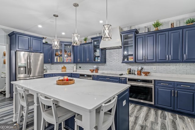 kitchen featuring blue cabinetry, a breakfast bar, decorative light fixtures, a kitchen island, and appliances with stainless steel finishes