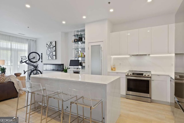 kitchen featuring stainless steel electric range oven, white cabinets, a center island, and light countertops