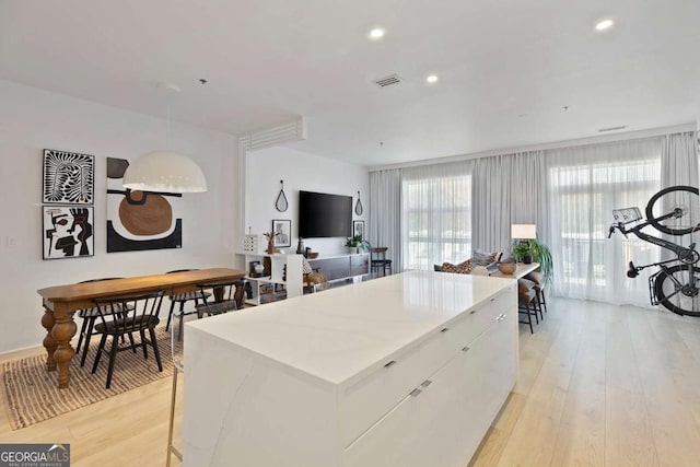 kitchen with light wood finished floors, visible vents, white cabinets, and a kitchen island