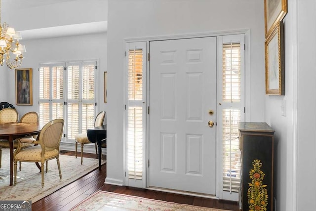 foyer entrance with dark hardwood / wood-style floors and an inviting chandelier