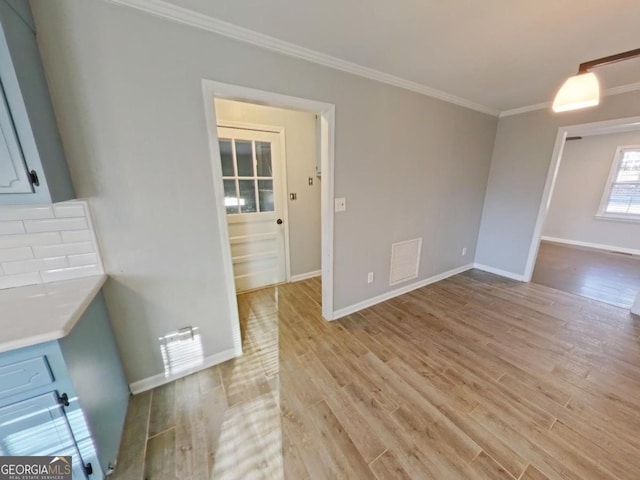 unfurnished dining area featuring ornamental molding and light hardwood / wood-style floors