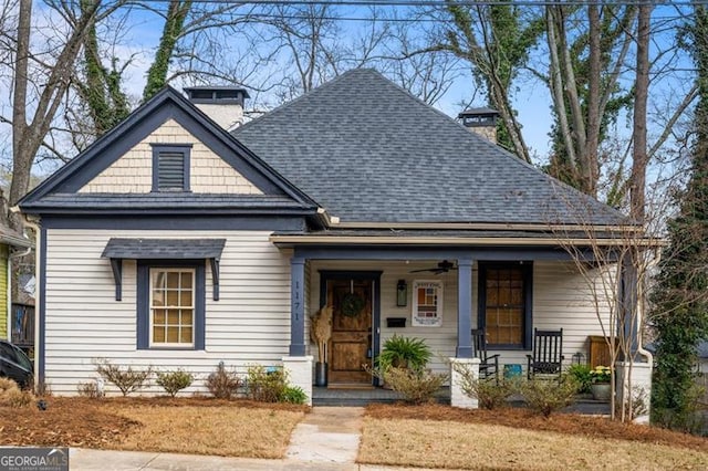 view of front of property with a shingled roof, a chimney, and a porch