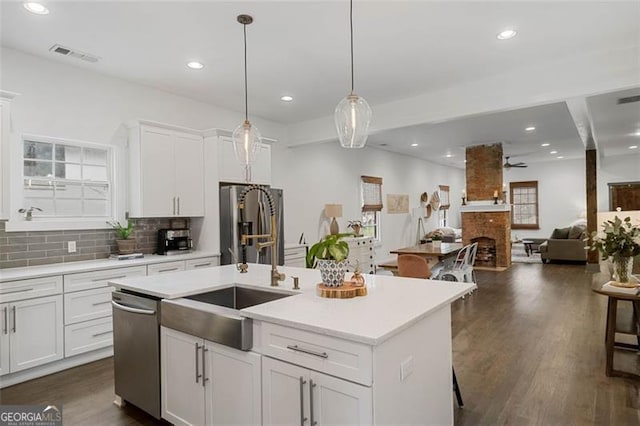 kitchen featuring an island with sink, white cabinetry, appliances with stainless steel finishes, and light countertops