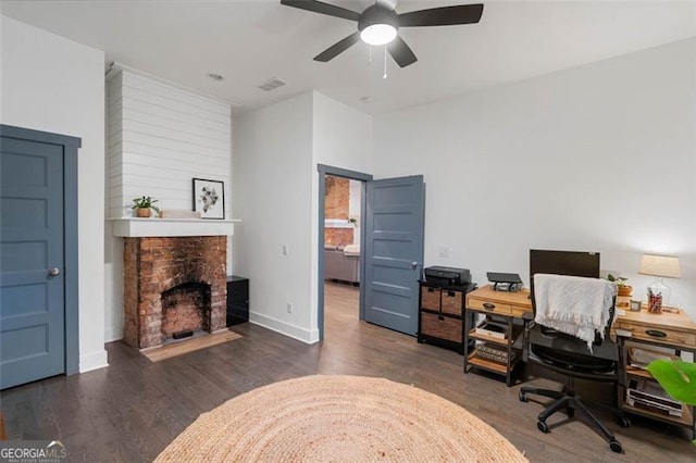 office with ceiling fan, a fireplace, visible vents, baseboards, and dark wood finished floors