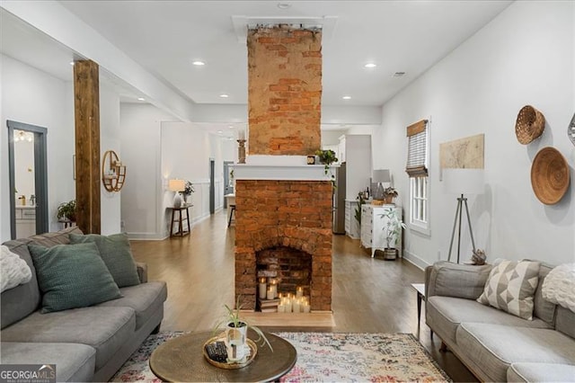 living room with a brick fireplace, wood finished floors, and recessed lighting