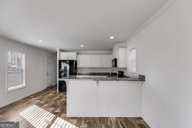 kitchen with white cabinetry, kitchen peninsula, black appliances, and dark hardwood / wood-style flooring