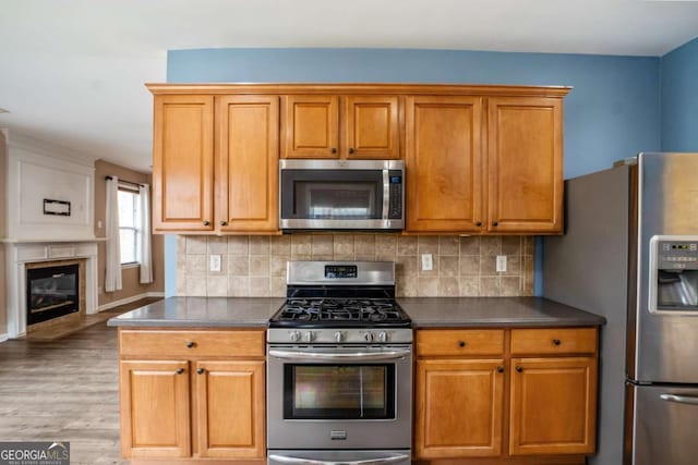 6498 Stonelake Pl SW, Atlanta, GA 30331 - kitchen featuring appliances with stainless steel finishes, dark countertops, light wood-style flooring, and decorative backsplash