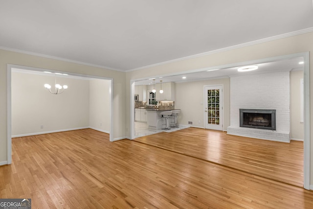 unfurnished living room featuring light wood finished floors, a brick fireplace, and crown molding