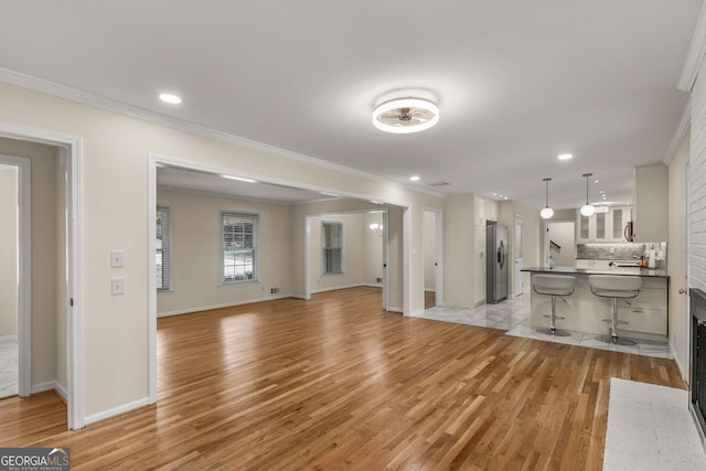 living room featuring ornamental molding, recessed lighting, light wood-style flooring, and baseboards