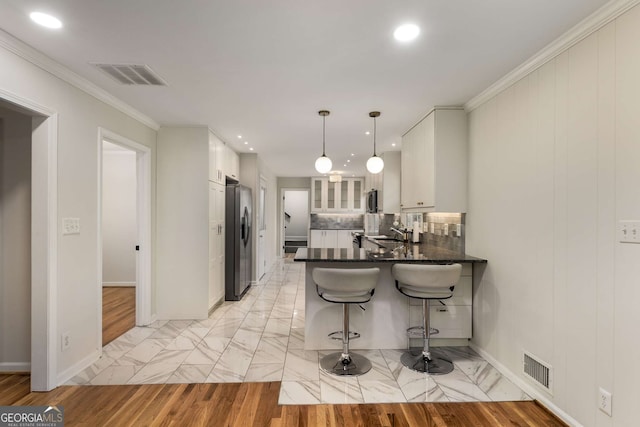 kitchen featuring a peninsula, visible vents, white cabinets, and hanging light fixtures