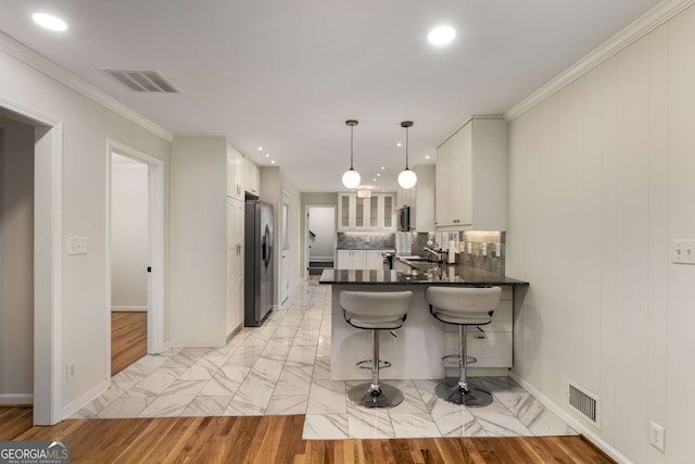 2542 Maclaren, Dunwoody, GA 30360 - kitchen featuring stainless steel appliances, a peninsula, white cabinets, a breakfast bar area, and crown molding