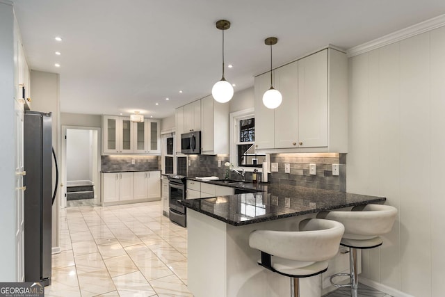 kitchen with a breakfast bar, hanging light fixtures, appliances with stainless steel finishes, white cabinets, and a peninsula