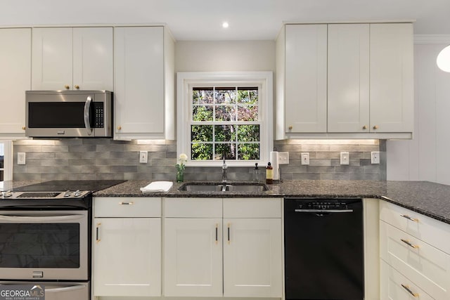 kitchen featuring tasteful backsplash, dark stone countertops, stainless steel appliances, white cabinetry, and a sink