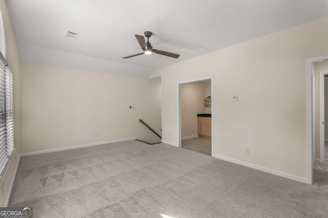 unfurnished bedroom with lofted ceiling, baseboards, visible vents, and light colored carpet