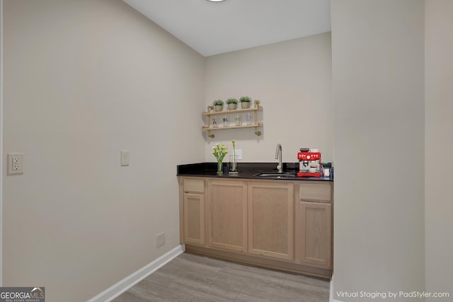 bar with wet bar, baseboards, and a sink