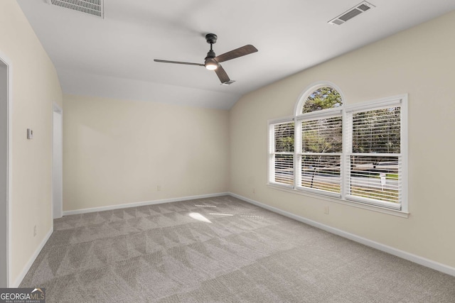 spare room with light carpet, baseboards, visible vents, and vaulted ceiling