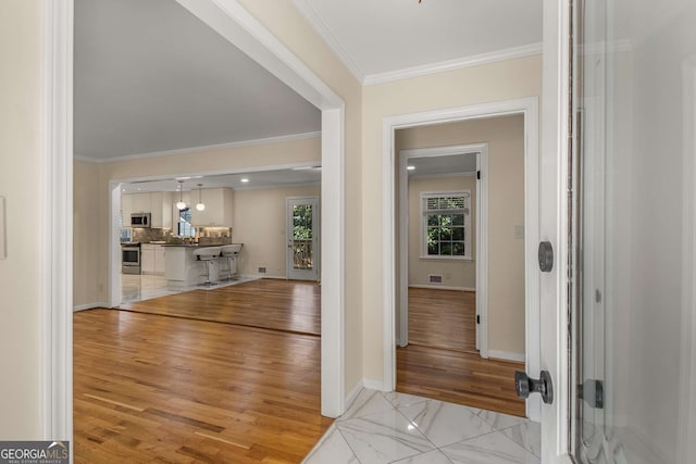 entryway with marble finish floor, baseboards, and crown molding