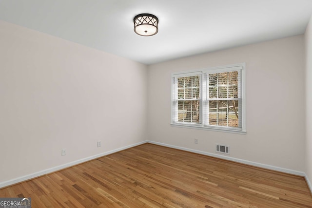 empty room featuring visible vents, light wood-style flooring, and baseboards