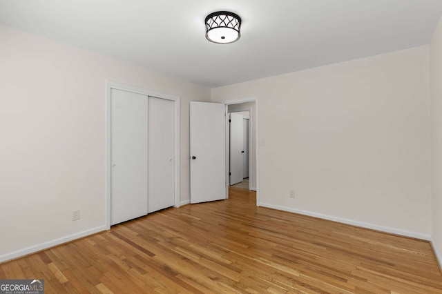 unfurnished bedroom featuring a closet, light wood-style flooring, and baseboards