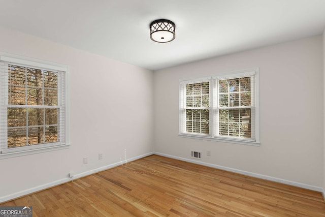 spare room featuring baseboards, visible vents, and light wood finished floors