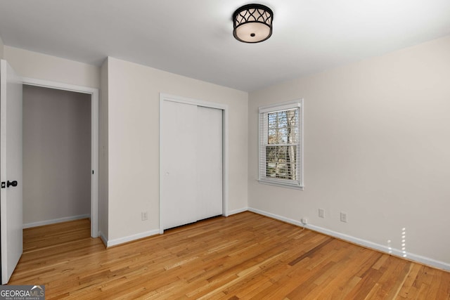 unfurnished bedroom with light wood finished floors, baseboards, and a closet