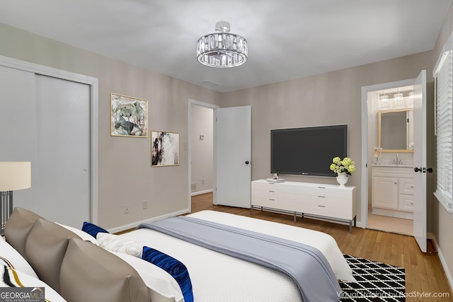 bedroom with a closet, ensuite bathroom, wood finished floors, a chandelier, and baseboards