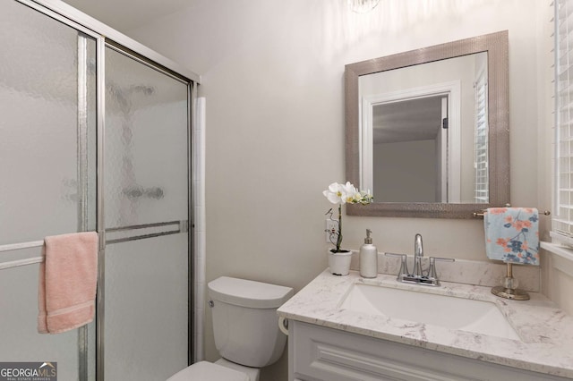 bathroom featuring toilet, a shower with shower door, and vanity