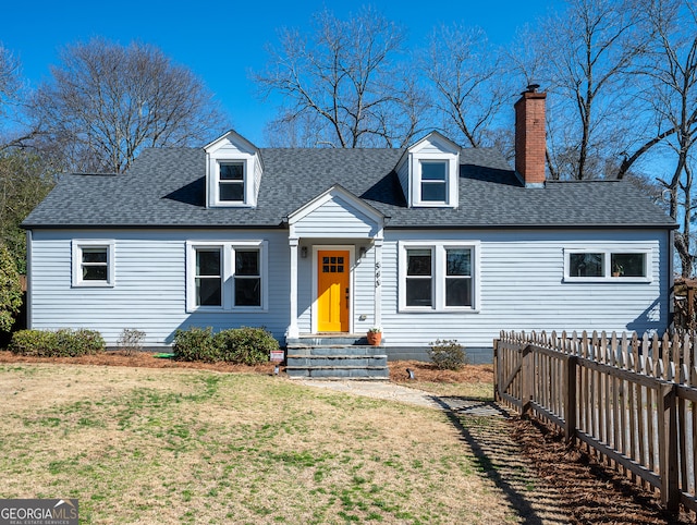 new england style home with entry steps, fence, roof with shingles, a front lawn, and a chimney