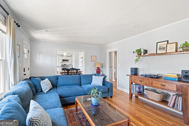 living room with plenty of natural light, crown molding, baseboards, and wood finished floors