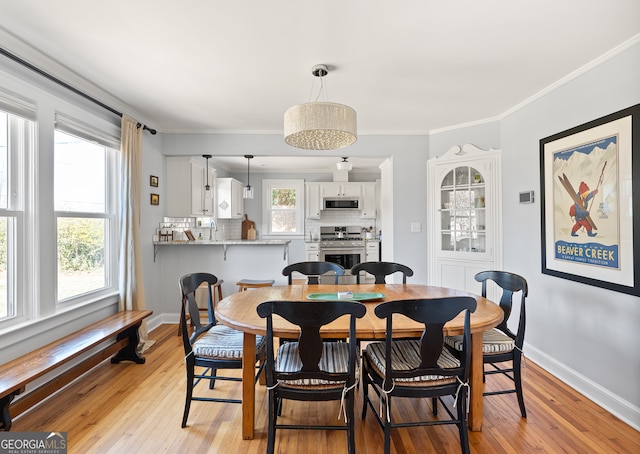 dining space with light wood-style flooring, baseboards, and ornamental molding