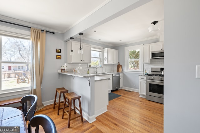 kitchen with stainless steel appliances, a peninsula, a breakfast bar, white cabinets, and hanging light fixtures