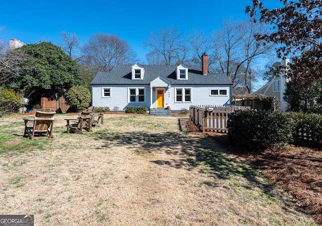 back of property with an outdoor fire pit, roof with shingles, a yard, and a chimney