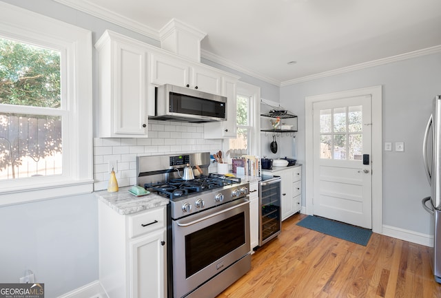 kitchen with beverage cooler, stainless steel appliances, and white cabinetry