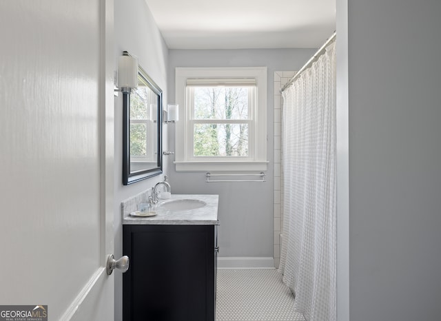 full bath featuring curtained shower, vanity, and baseboards