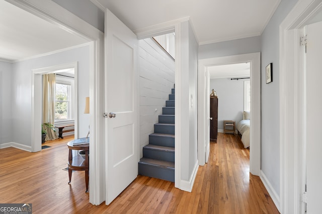 stairway with ornamental molding, wood finished floors, and baseboards