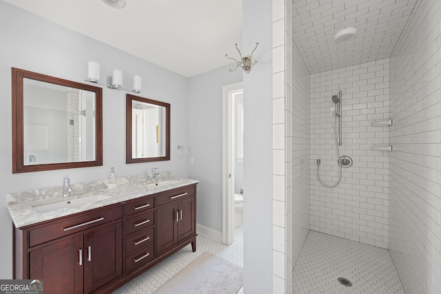 full bath with baseboards, a sink, toilet, and double vanity