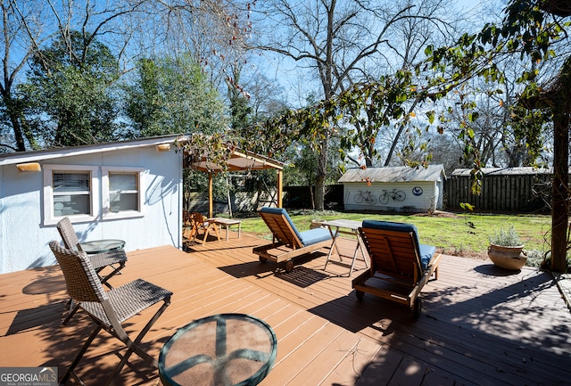 deck featuring a storage unit, a lawn, an outdoor structure, and a fenced backyard