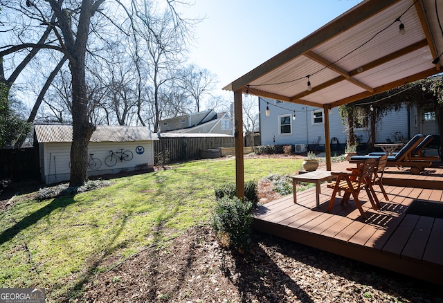 view of yard featuring outdoor dining area, a fenced backyard, an outdoor structure, and a deck