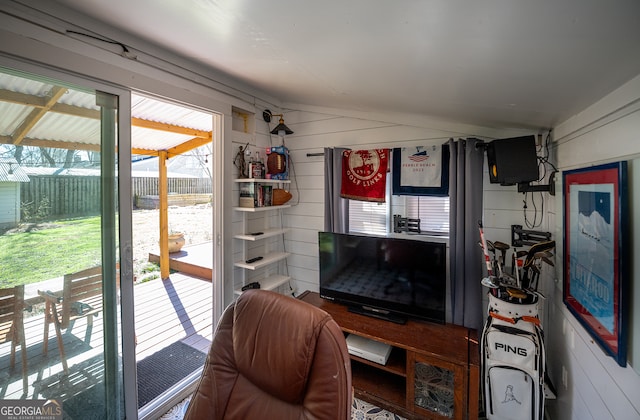 living area with wooden walls and vaulted ceiling