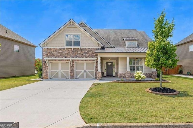 craftsman house with a standing seam roof, a garage, stone siding, a front yard, and concrete driveway