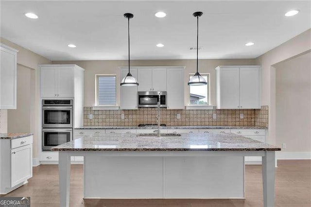kitchen featuring stainless steel appliances, white cabinets, and backsplash