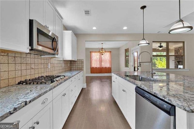 kitchen featuring appliances with stainless steel finishes, a wealth of natural light, white cabinetry, and a sink