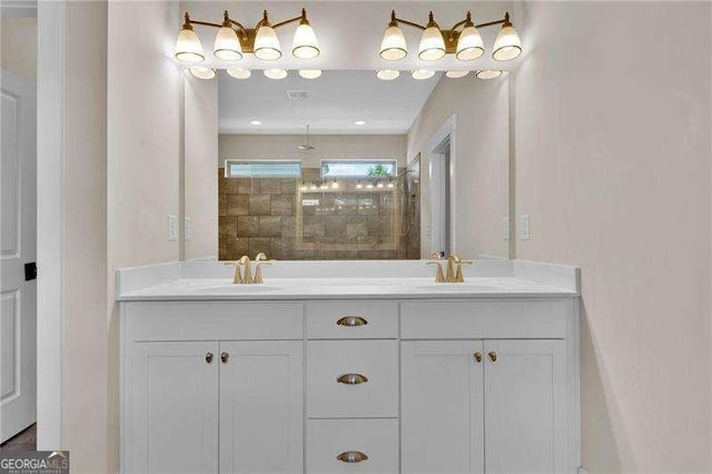 bathroom featuring double vanity, tiled shower, and a sink